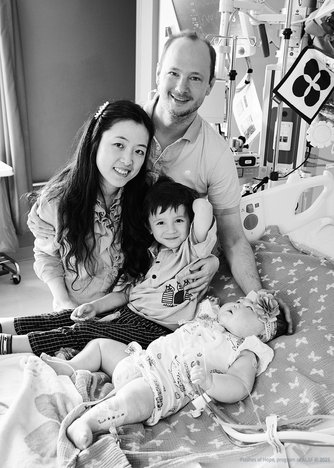 Black and white of Mommy and Daddy with Declan and Constance on a bed.
